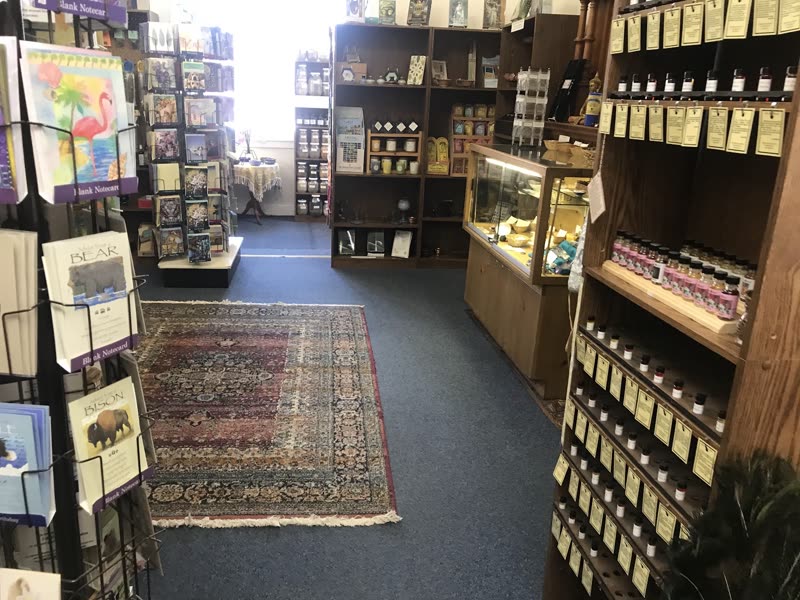 Front of the shop with dark wood shelving, a patterned rug and a card rack