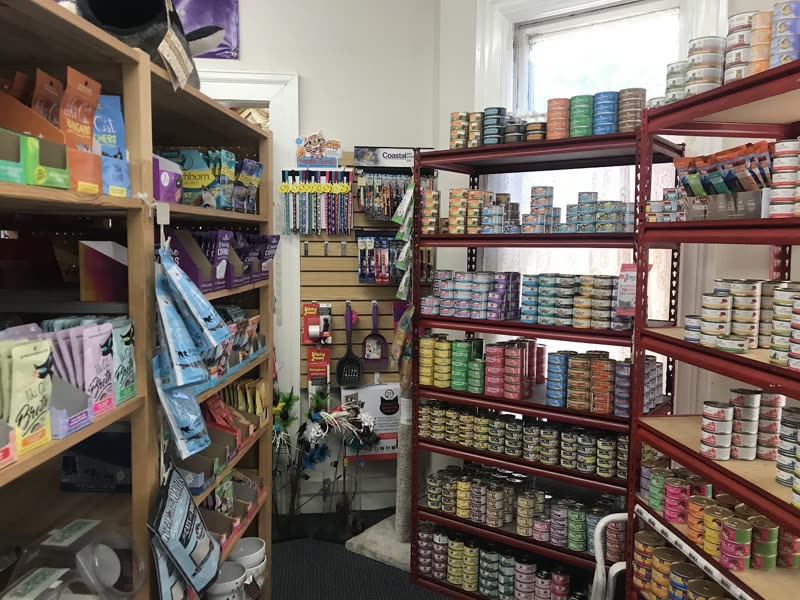 Wide shop aisle with floor-to-ceiling red shelving packed with tinned and boxed pet food