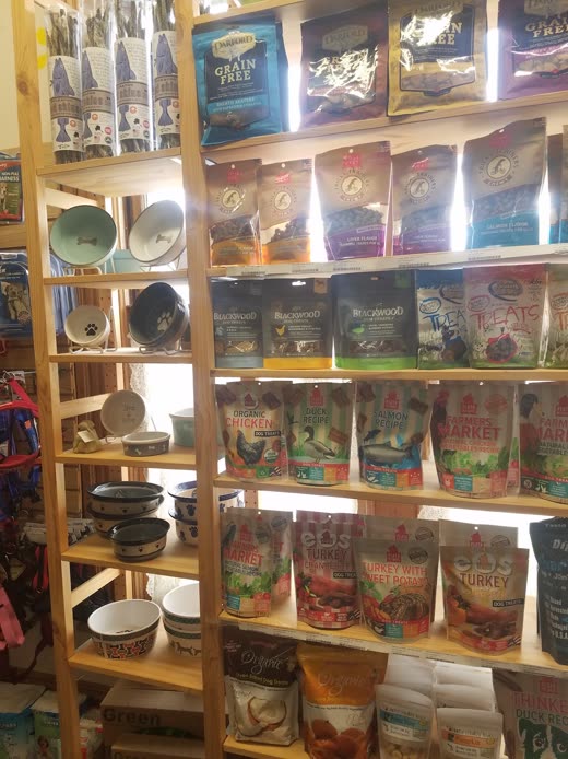 Wooden shelving stocked with bags of pet food and ceramic feeding bowls